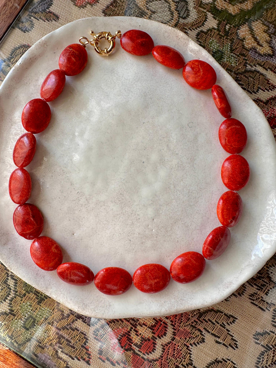 Collar Paula de coral rojo sobre plato de cerámica