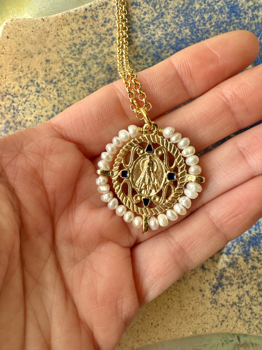 Medalla de la Virgen de Fátima con perlas y esmalte azul marino en la mano