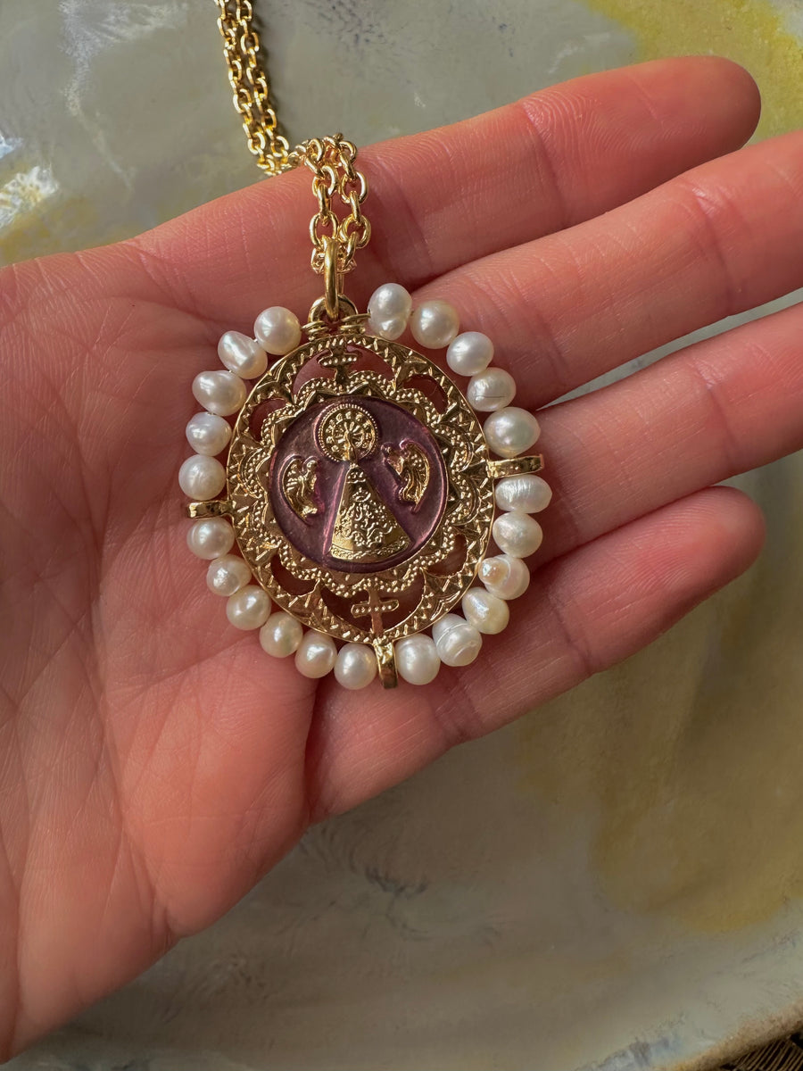 Medalla de la Virgen del Pilar con perlas naturales y esmalte lila en la mano